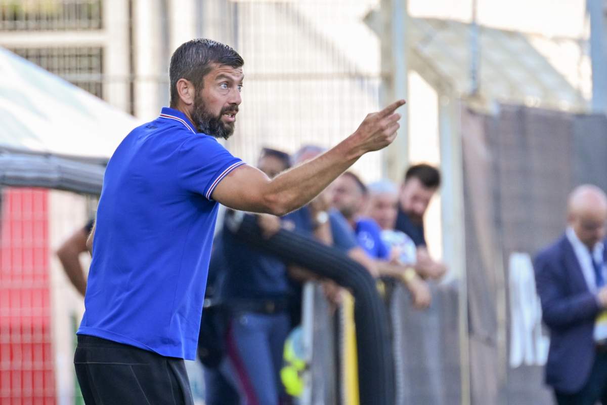 Massimo Donati in primo piano, di profilo, in piedi davanti alla panchina e con l'indice puntato